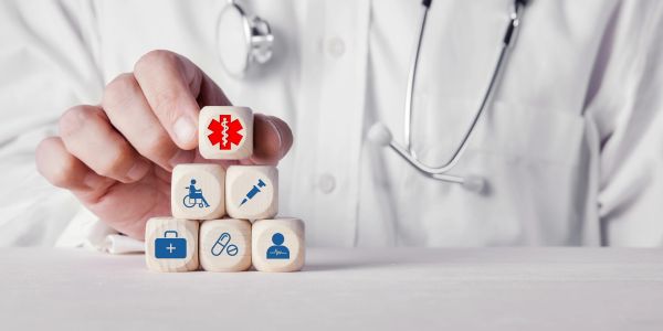 Doctor stacking wooden blocks with medical icons symbolizing healthcare.