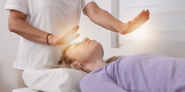 Person performing energy healing on a lying woman.