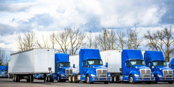 Line of blue and white semi-trucks parked outdoors.