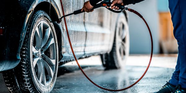 Person washing a car with a high-pressure hose.