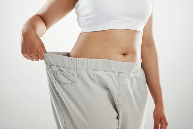 Studio shot of an unrecognizable woman trying on a pair of loose fitting pants against a gray background