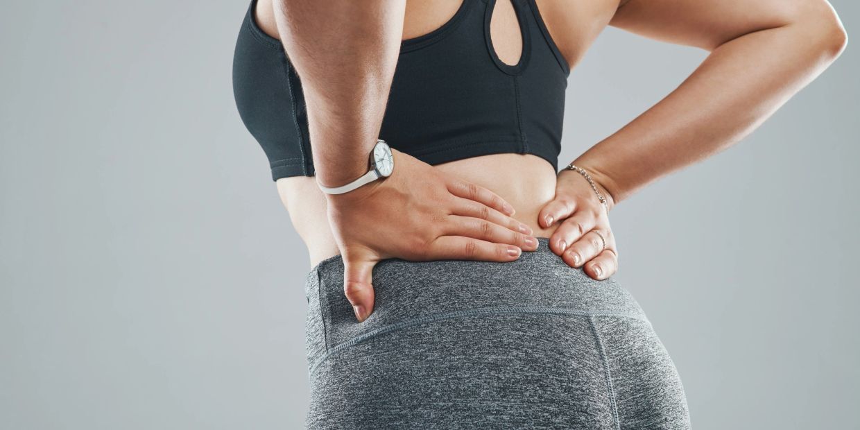 Person holding lower back in pain.