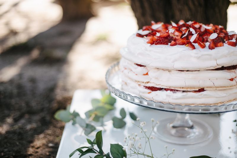 White crust cake with strawberries on top on a plate in the garden. Wedding cake. Meringue, Pavlova cake