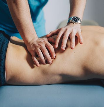 Hands performing a deep tissue massage on a person's back.