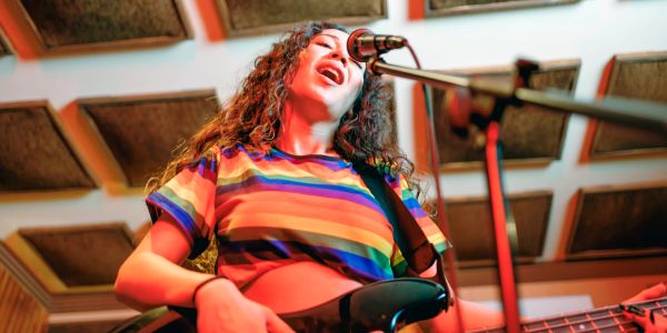 Woman singing and playing bass guitar.