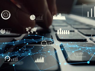 Close-up of hands typing on a keyboard with digital data graphs.