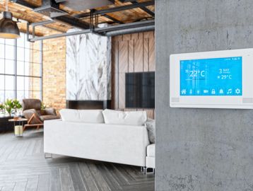 Smart thermostat on a wall in a modern living room.