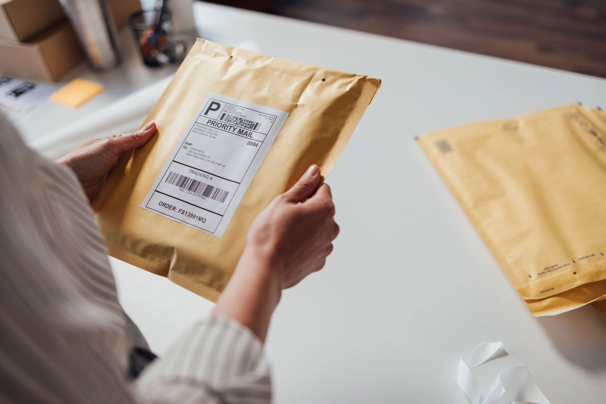 Person holding a priority mail package with shipping label.
