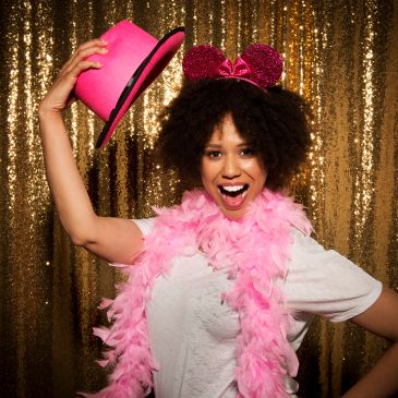 Excited woman in pink accessories against gold backdrop.
