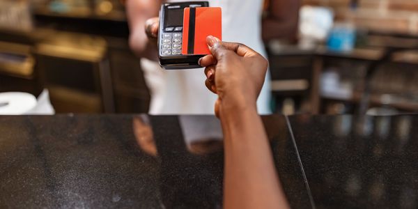 Person making a contactless payment with a red card at a store counter.