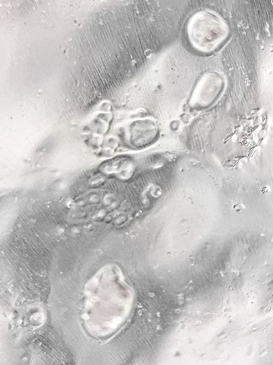 Close-up of bubbles trapped in clear ice with textured surface.