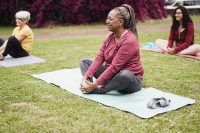 Three women practicing yoga outdoors.