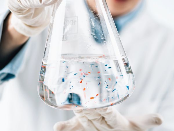 Scientist holds flask with water containing microplastics for analysis.