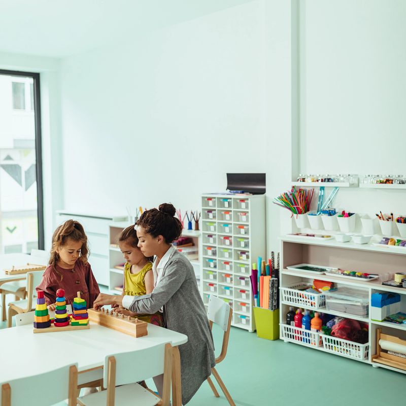 Teacher and little girls being creative with some toys at kindergarten