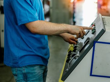 Person operating control panel in an industrial setting.