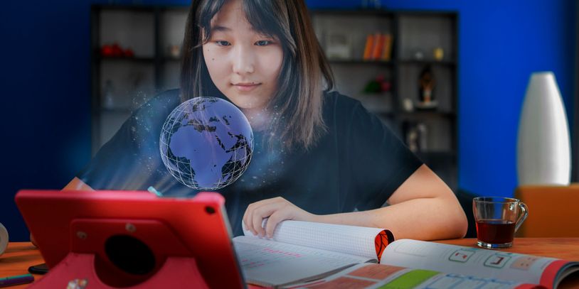 A young woman studying with a red tablet and a holographic globe above her notebook.