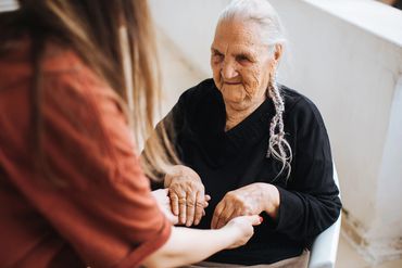 Elderly woman holding hands with a younger person, sharing a tender moment.