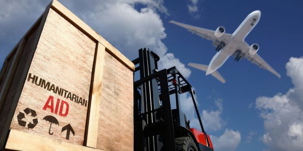 Humanitarian aid crate with airplane and forklift outdoors.