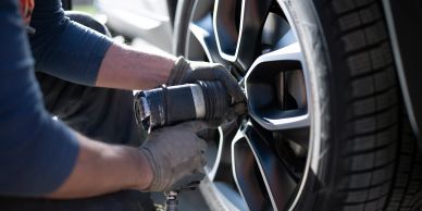 Un mécanicien change une roue de voiture avec un outil.