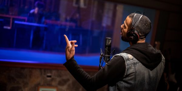 Man singing in a recording studio with headphones.