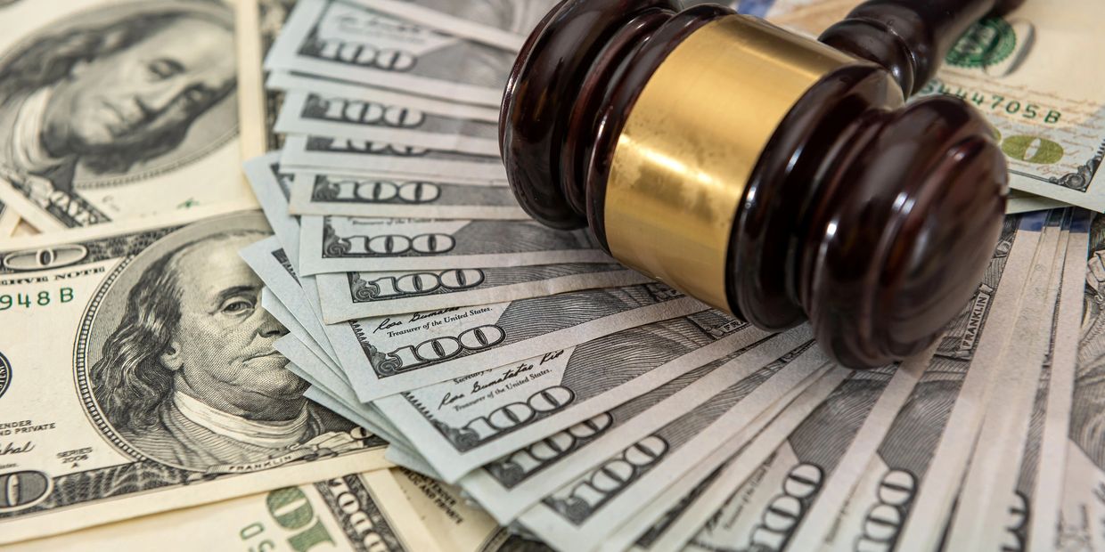 Judge's gavel rests on a pile of US dollar bills.