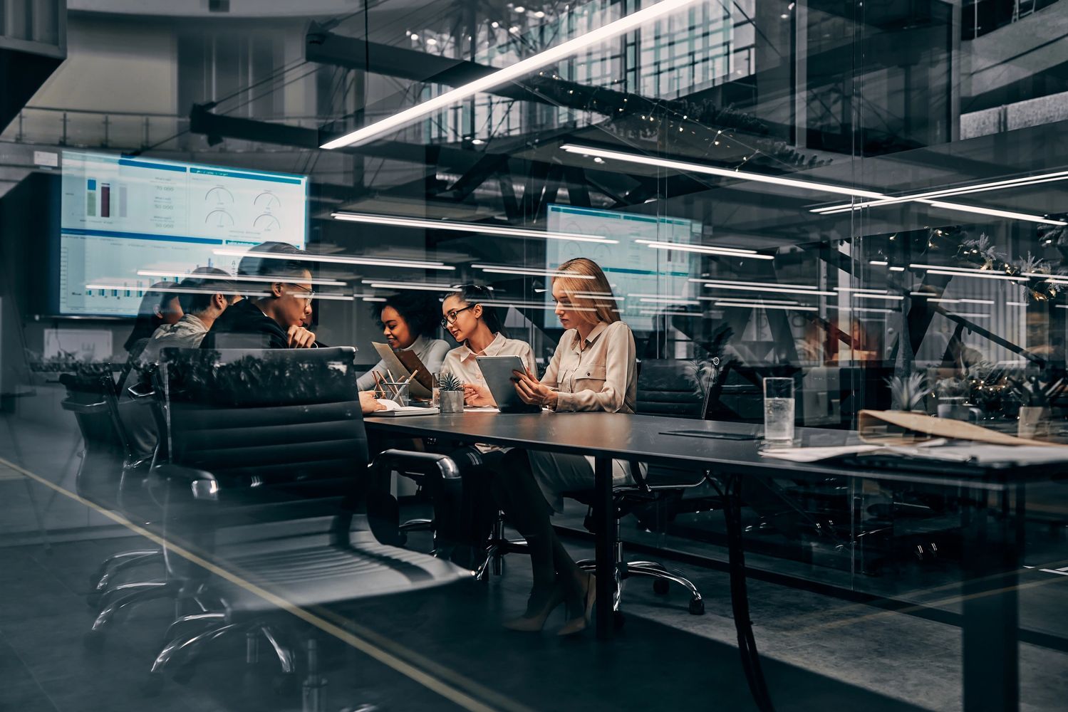 Team meeting in a modern office with digital data displays.