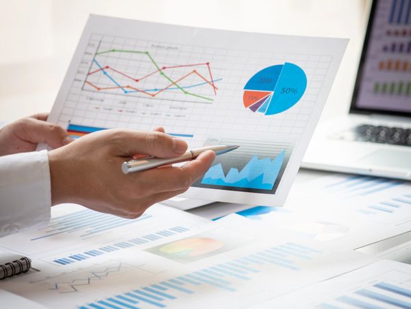 Person analyzing financial charts and graphs with a pen.