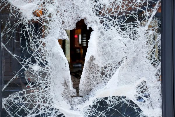Close-up of a shattered glass window with a large hole in the center.