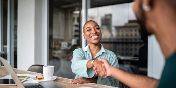 Two people shaking hands in a friendly office meeting.