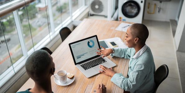 Two people review a financial projection report on a laptop in a bright room.