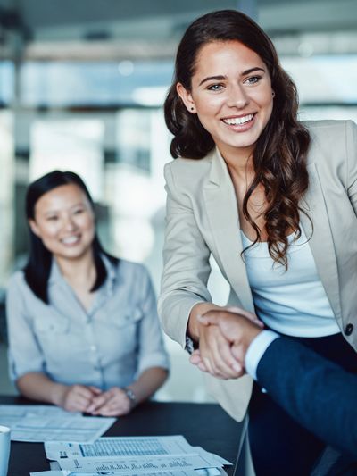 Professional handshake and smiling colleagues in a business meeting.
