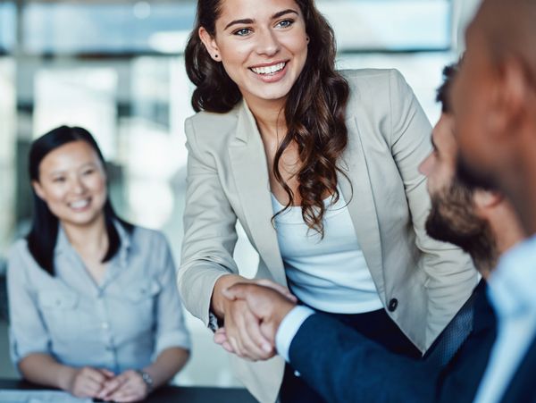 Smiling businesswoman shaking hands in a modern office meeting.