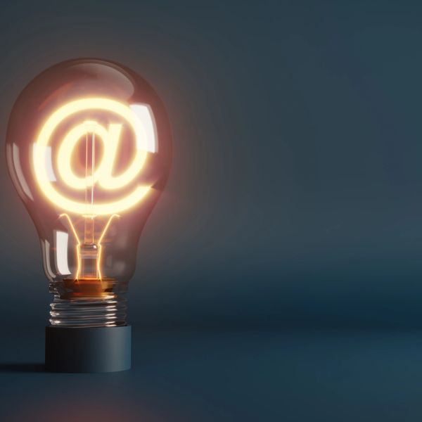 Light bulb glowing with an illuminated @ symbol inside.