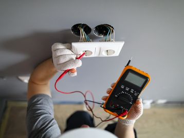 Electrician testing wall sockets with a multimeter.