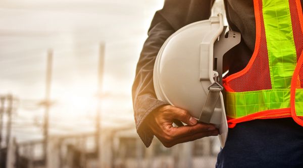 Construction worker holding a white safety helmet.