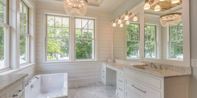 Bright bathroom with large windows, a soaking tub, and marble countertops.