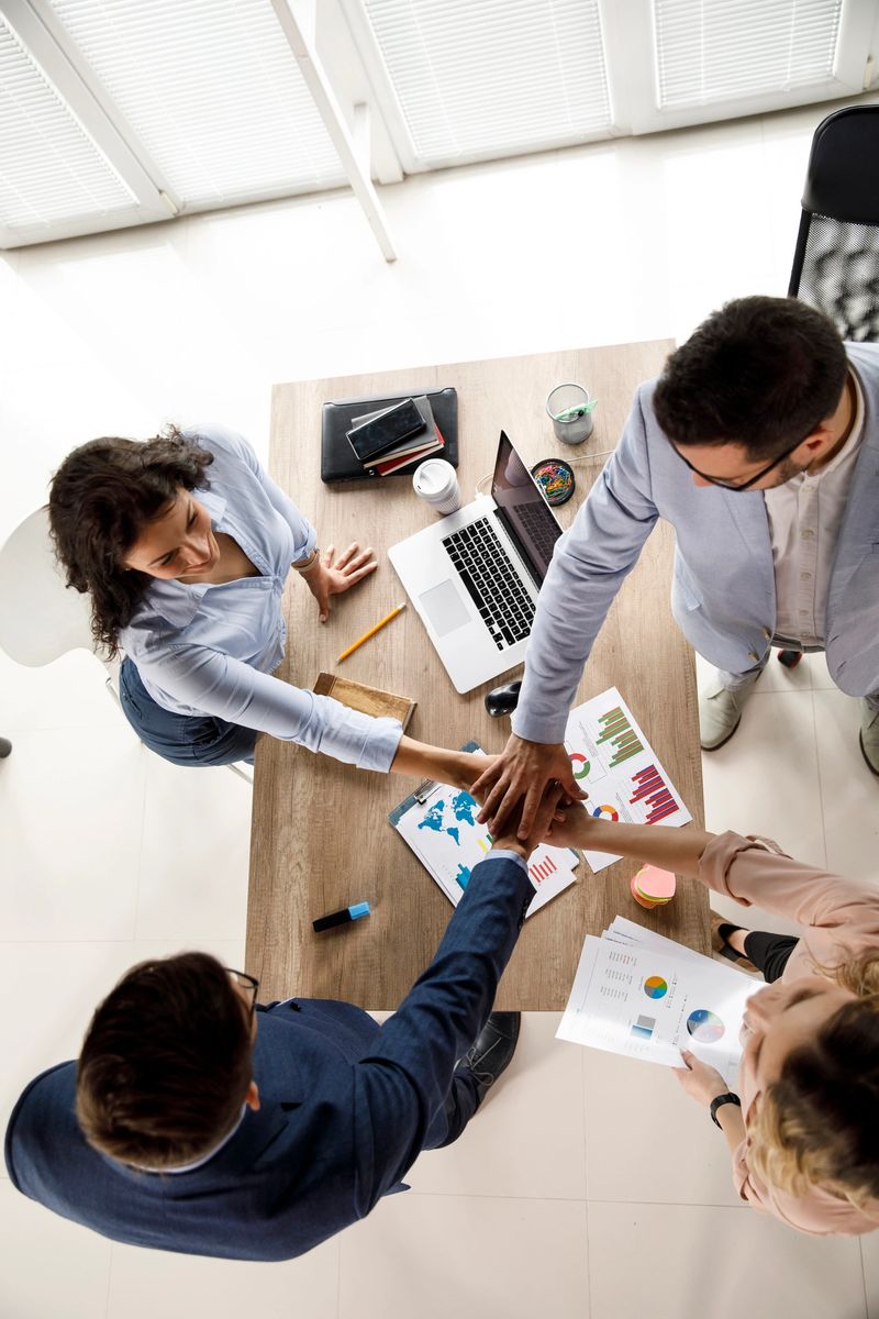High angle shot of a group of business colleagues joining their hands together in unity after concluding a successful business meeting.