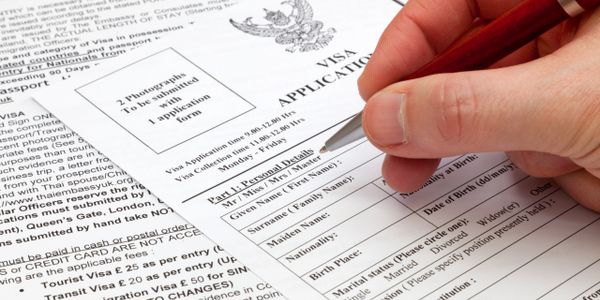 Filling out a visa application form with a pen in hand.