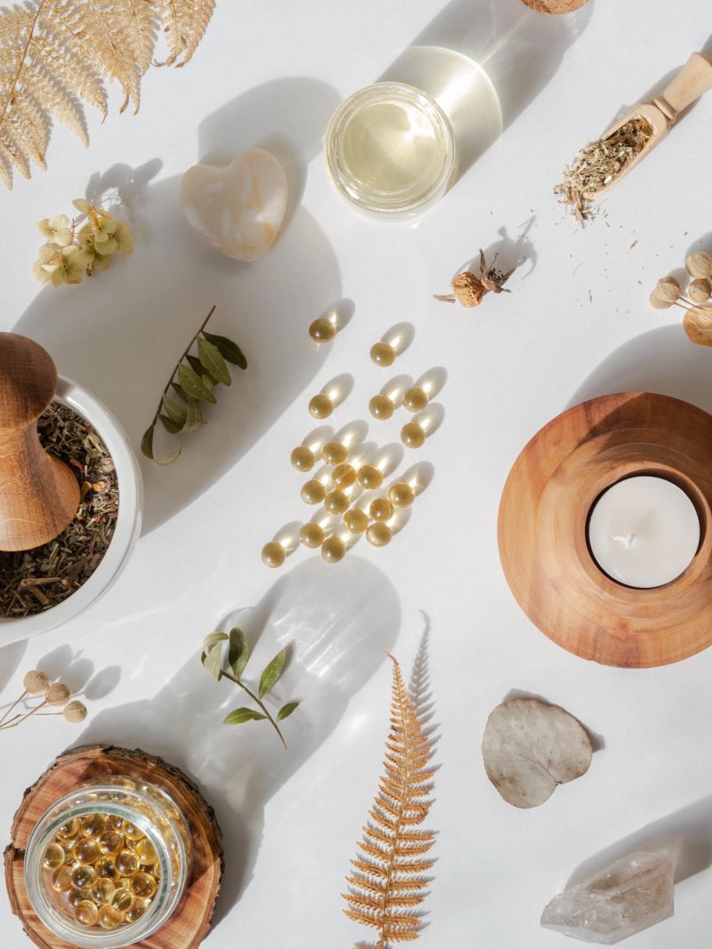 Organic natural product - oils and various dry plants for health on white background in the sunlight. Herbal alternative medicine and aromatherapy. Top view