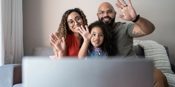 Family waving at a screen, video chatting.