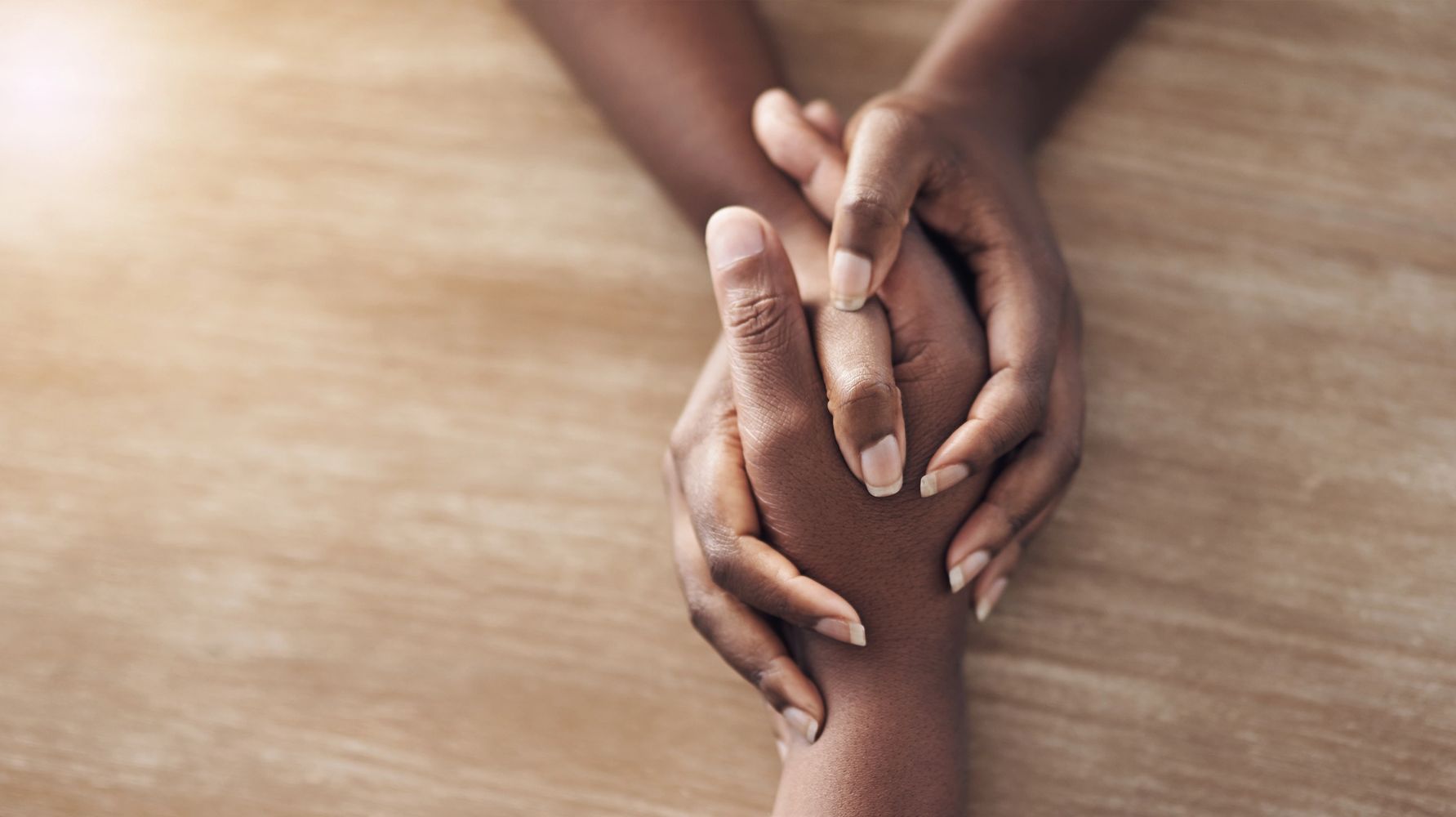 Two hands gently holding each other in a comforting gesture.