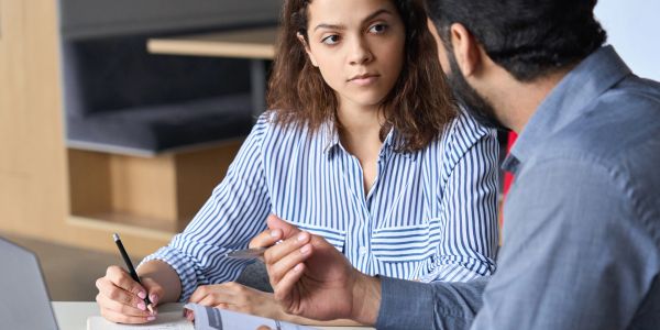 Two colleagues discussing work in an office.