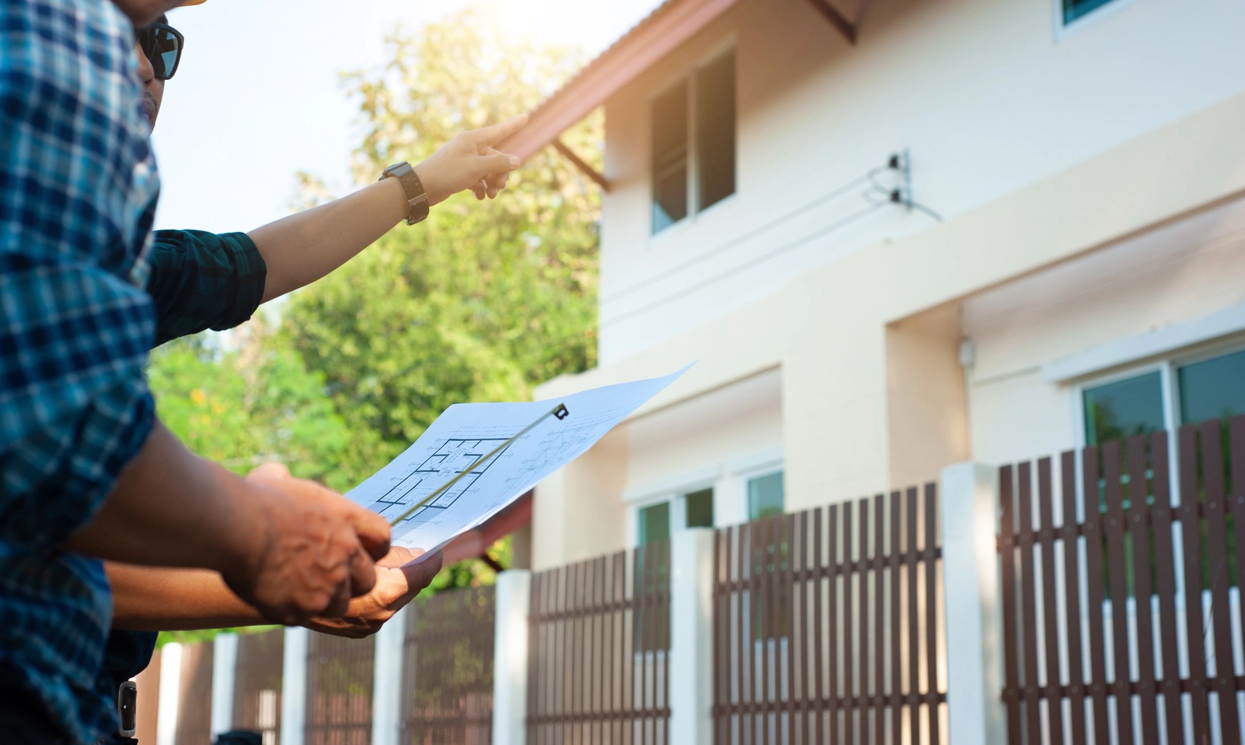 Two men discussing house plans outside a residential building.
