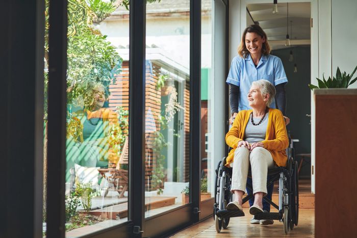 Smiling elderly woman sitting with a group of seniors in a cheerful setting.