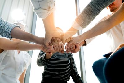 People joining hands in a group gesture.