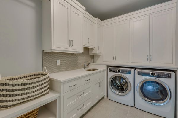 Modern laundry room with white cabinetry and washer-dryer.