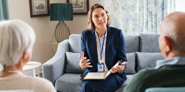 A professional woman consulting with an elderly couple at home.