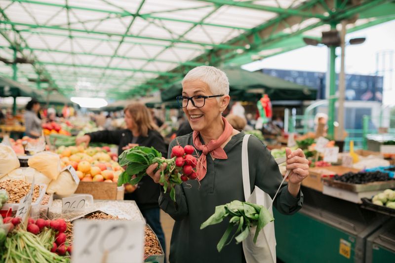 Happy elderly Caucasian woman with a short gray hair, shopping for groceries at the farmer's market, smiling