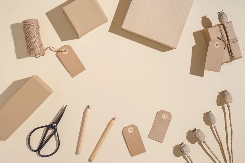 Creative layout with gift boxes with empty tag, handcrafted presents with craft paper decorated natural flower. Holiday, celebration and party concept.