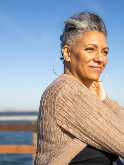 Woman standing on a pier looking content following her hypnosis and life coaching session in Matlock